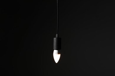 Photo of Glowing light bulb hanging on dark background