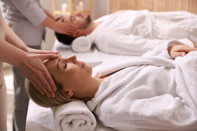 Photo of Couple receiving relaxing massage in spa salon, selective focus