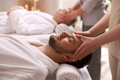 Photo of Couple receiving relaxing massage in spa salon, selective focus