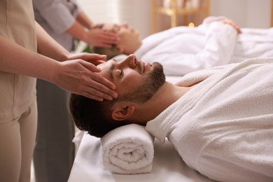 Photo of Couple receiving relaxing massage in spa salon, selective focus