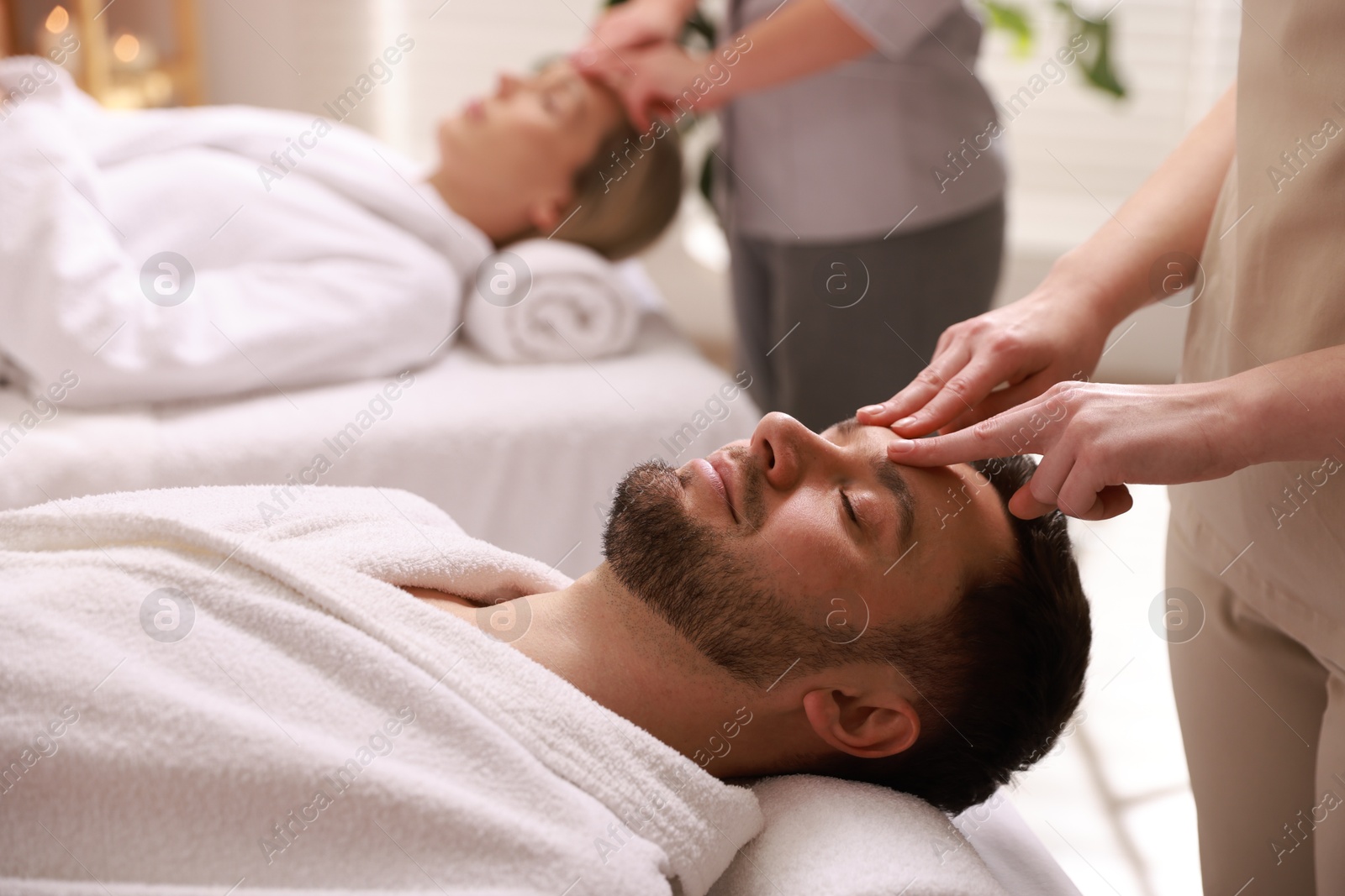 Photo of Couple receiving relaxing massage in spa salon, selective focus