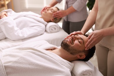 Photo of Couple receiving relaxing massage in spa salon, selective focus