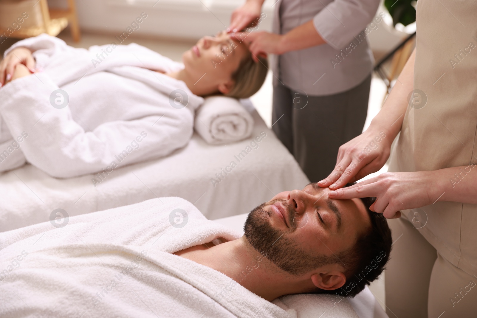 Photo of Couple receiving relaxing massage in spa salon, selective focus