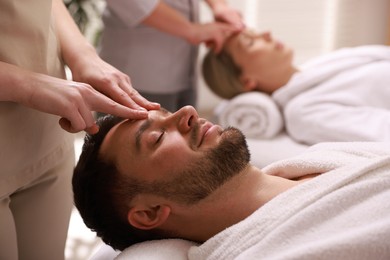 Photo of Couple receiving relaxing massage in spa salon, selective focus