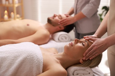 Photo of Couple receiving relaxing massage in spa salon, selective focus