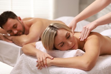 Photo of Couple receiving relaxing massage in spa salon, selective focus