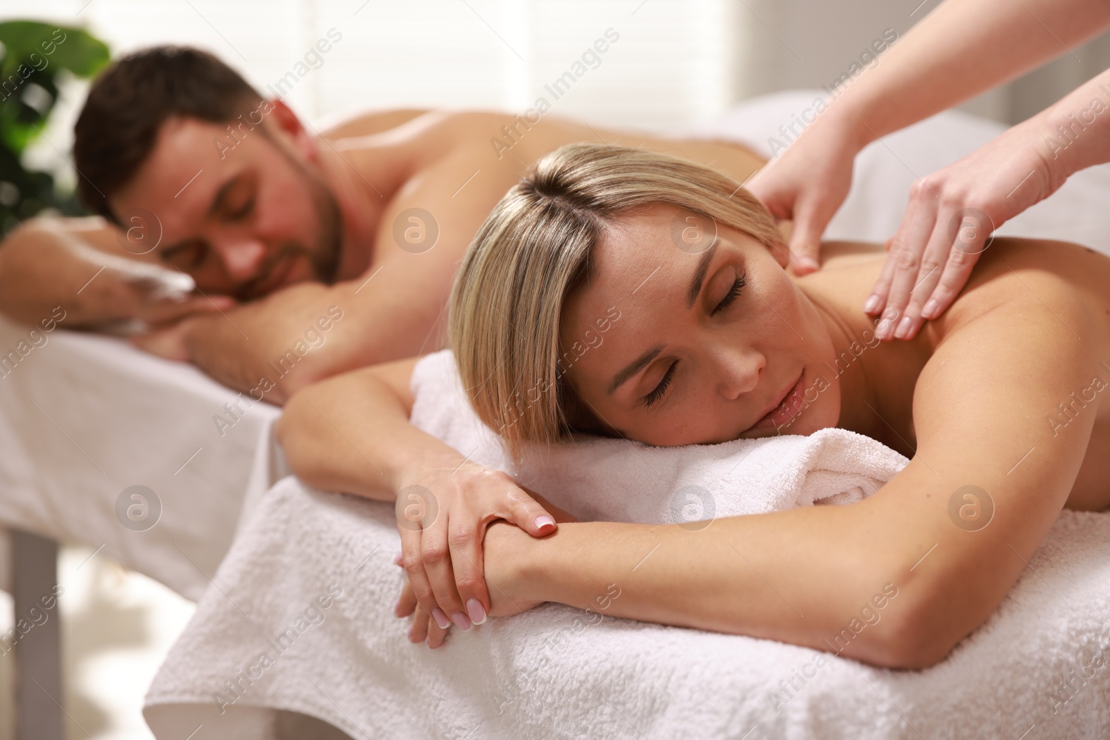 Photo of Couple receiving relaxing massage in spa salon, selective focus