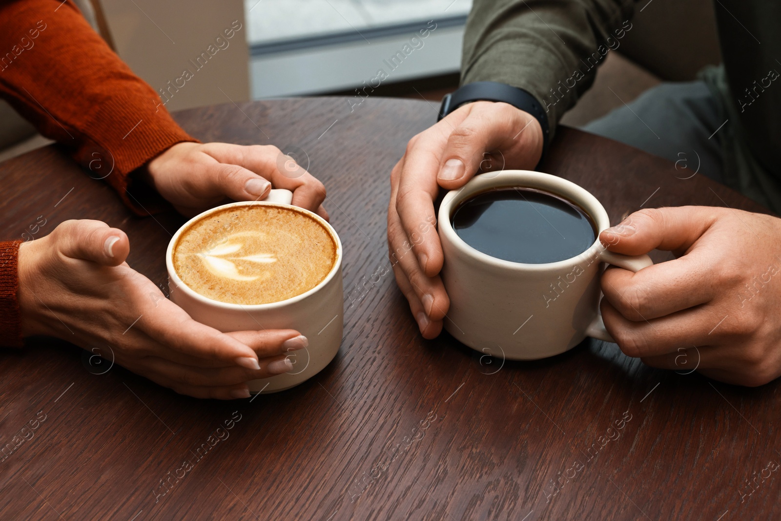 Photo of Colleagues having coffee break at wooden table in cafe, closeup