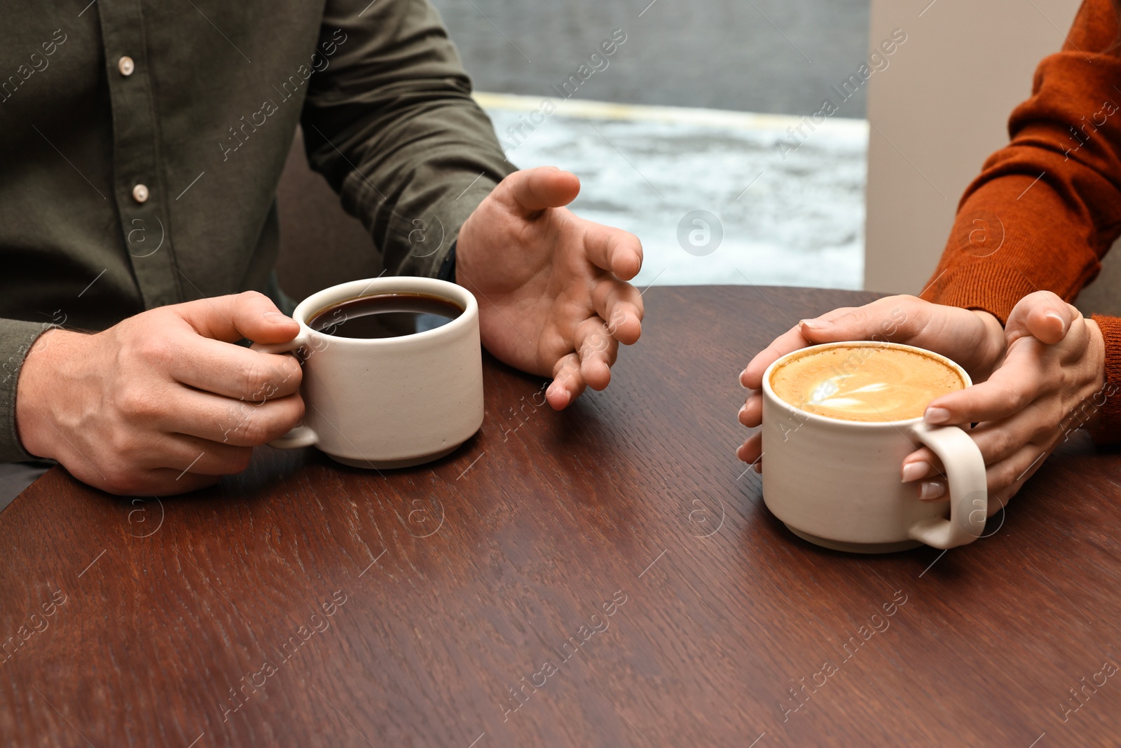 Photo of Colleagues having coffee break at wooden table in cafe, closeup