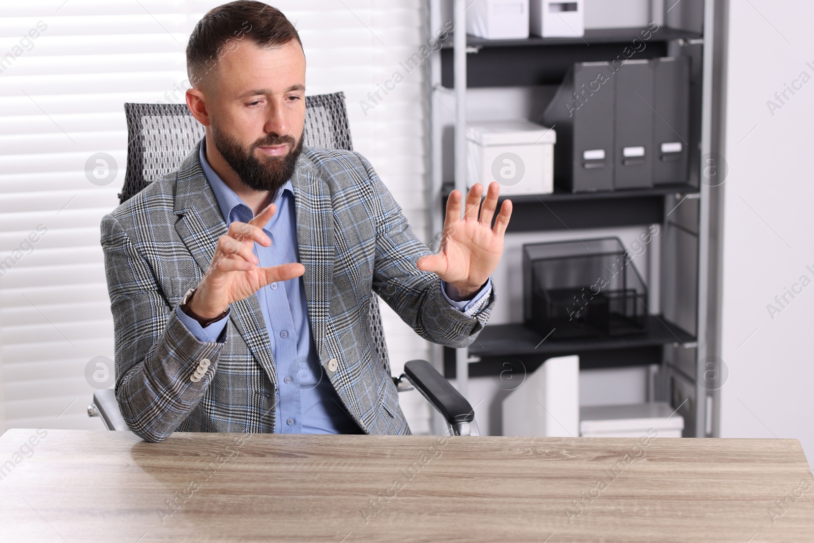 Photo of Man showing something at wooden desk in office, space for text