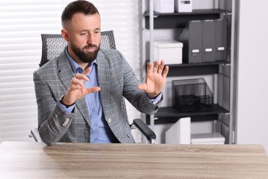 Photo of Man showing something at wooden desk in office, space for text