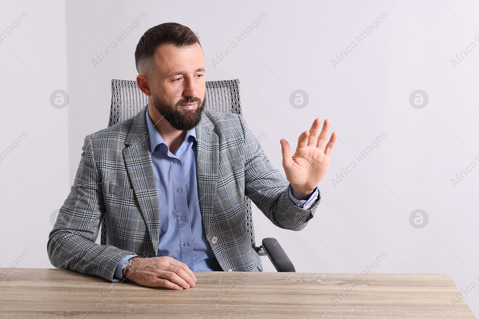 Photo of Man showing something at wooden desk in office, space for text