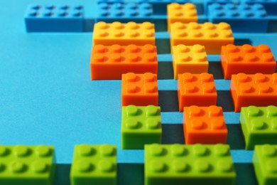 Photo of Construction toy. Colorful building bricks on light blue background, closeup