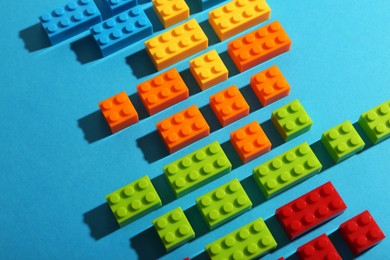 Photo of Construction toy. Colorful building bricks on light blue background, closeup