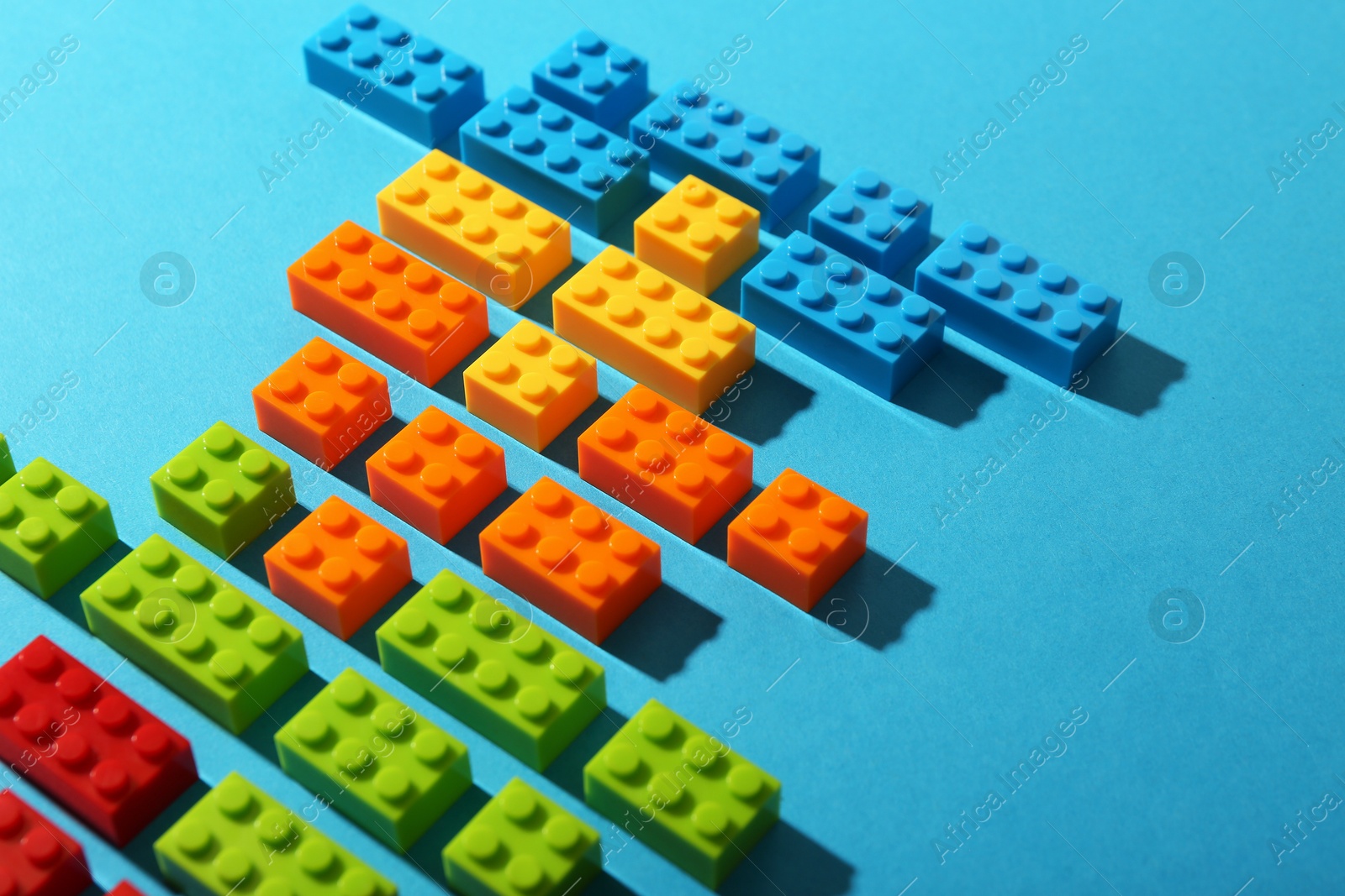 Photo of Construction toy. Colorful building bricks on light blue background, closeup