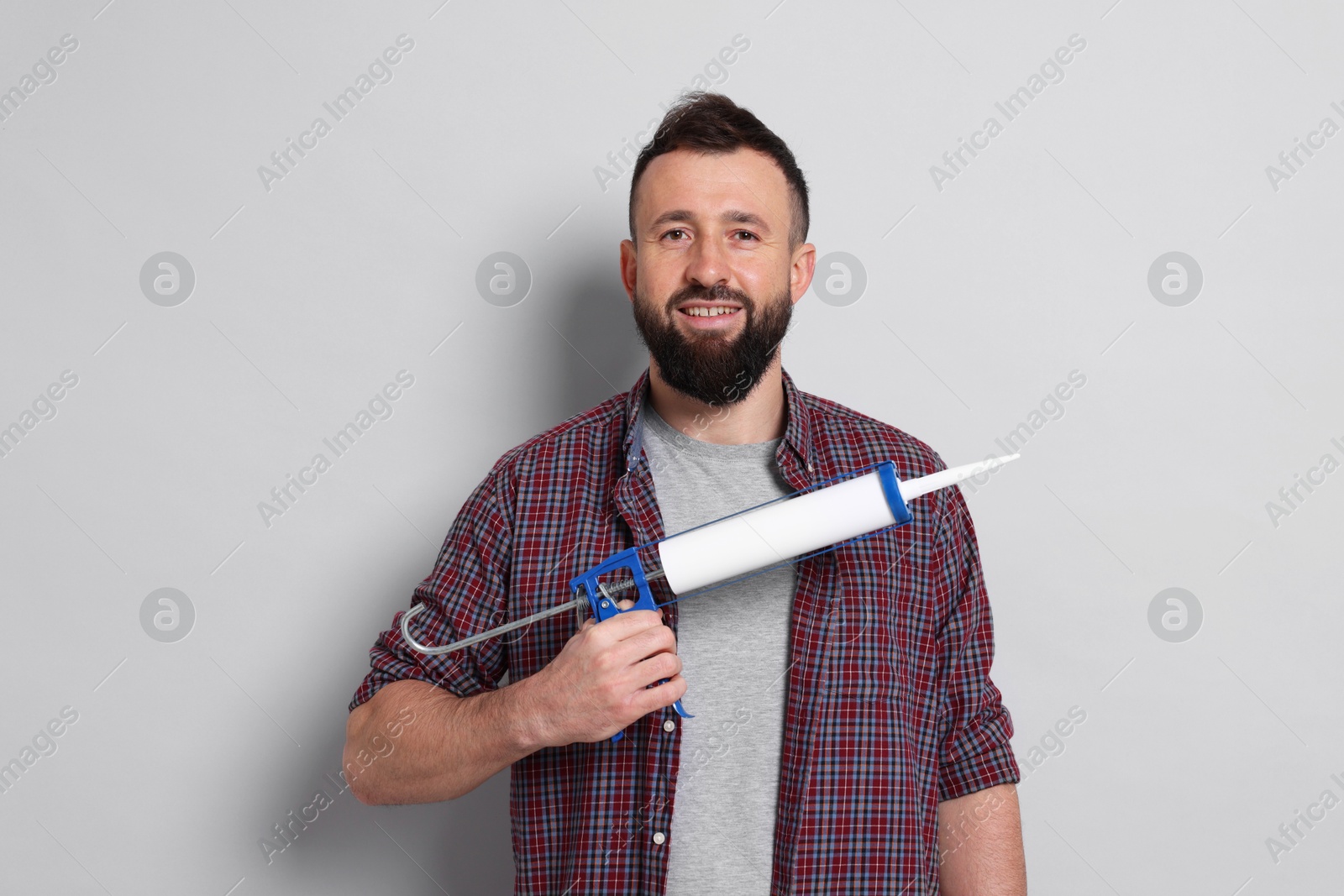 Photo of Man with caulking gun on gray background