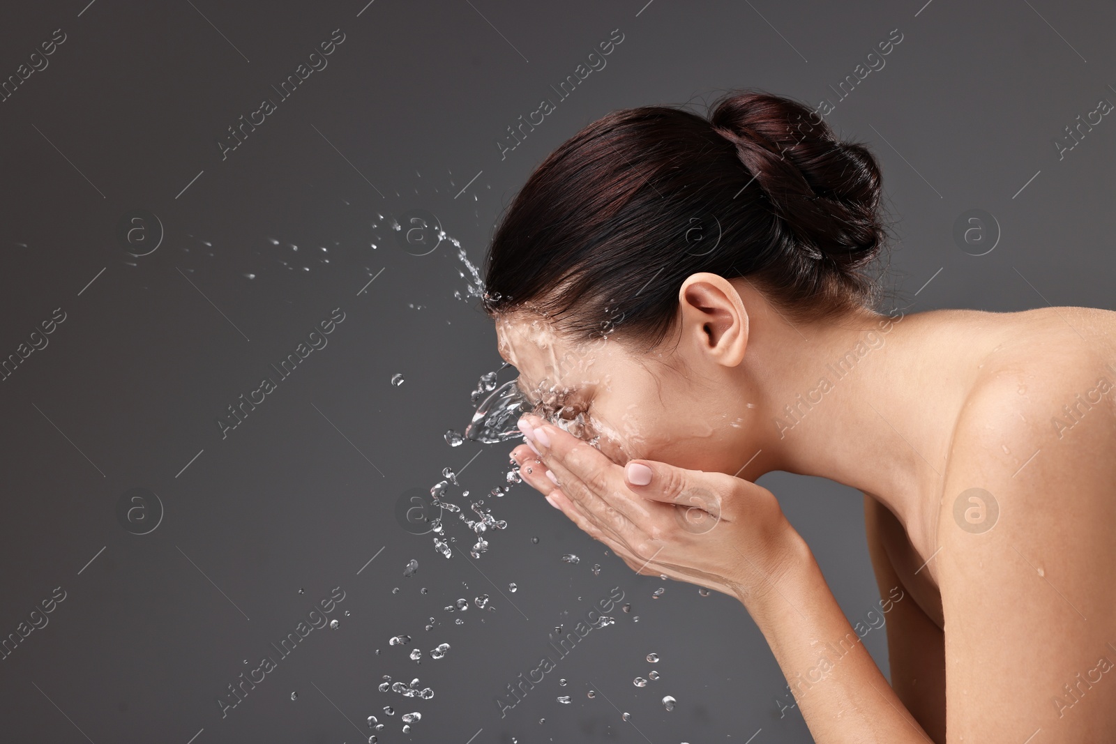 Photo of Woman washing her face on grey background, space for text