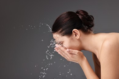 Photo of Woman washing her face on grey background, space for text