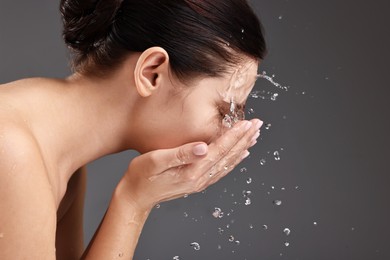 Photo of Woman washing her face on grey background, space for text