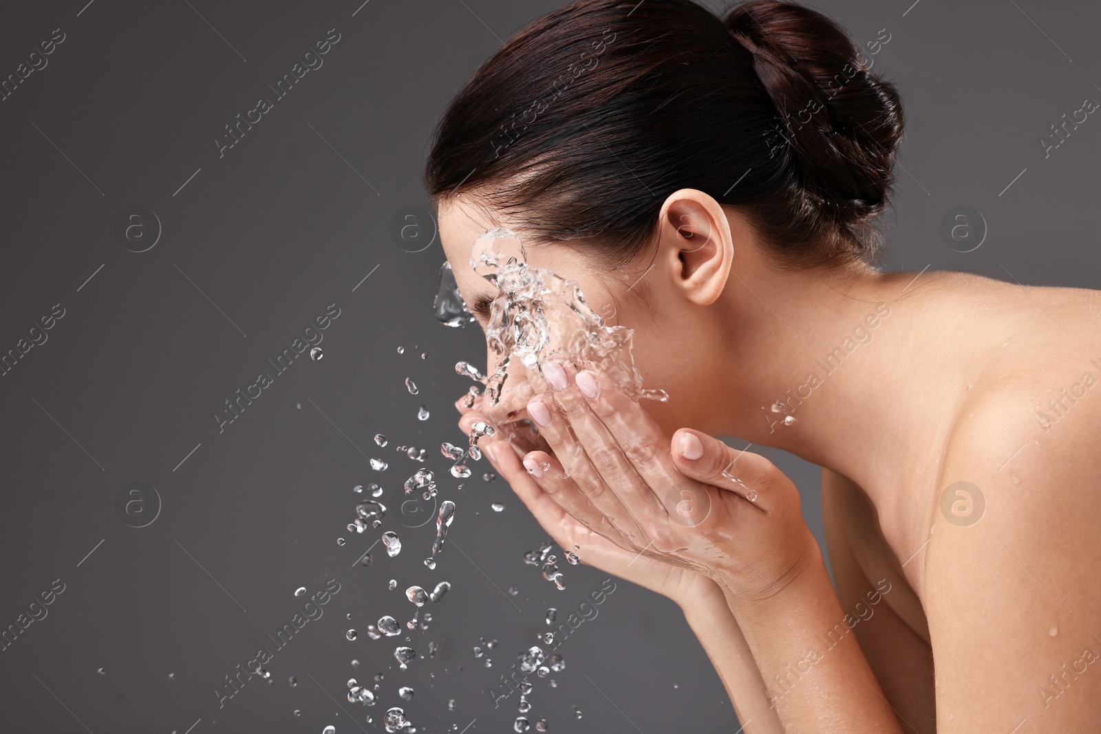 Photo of Woman washing her face on grey background, space for text