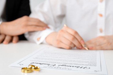 Photo of Newlyweds signing marriage contract and wedding rings on desk, selective focus