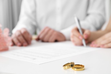 Photo of Newlyweds signing marriage contract and wedding rings on desk, selective focus