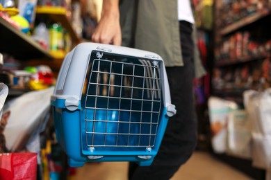 Photo of Woman with carrier in pet shop, closeup