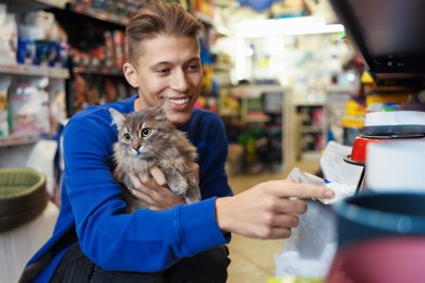 Photo of Man with his cute cat in pet shop