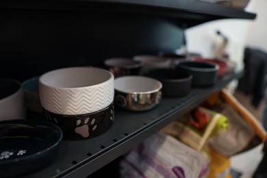 Photo of Different feeding bowls on shelf in pet shop, closeup