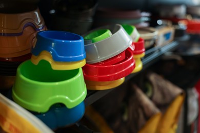 Photo of Different feeding bowls on shelf in pet shop, closeup