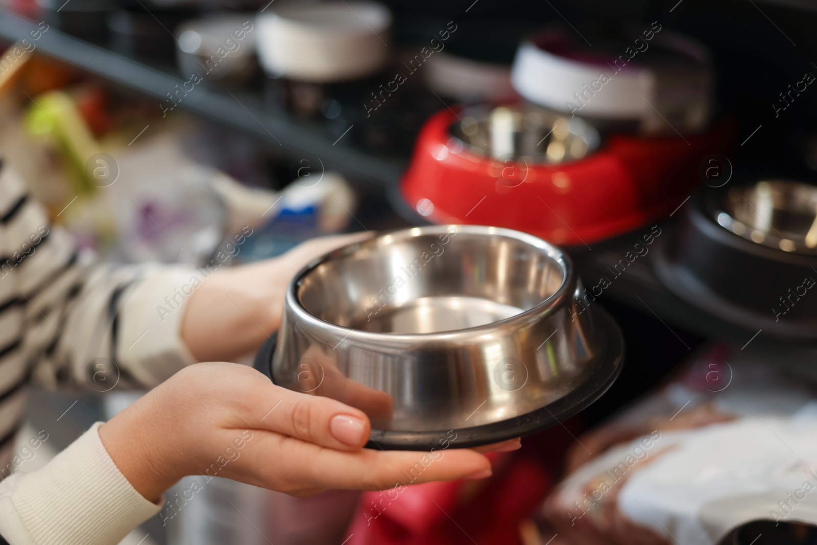 Photo of Woman choosing feeding bowl in pet shop, closeup