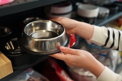 Photo of Woman choosing feeding bowl in pet shop, closeup