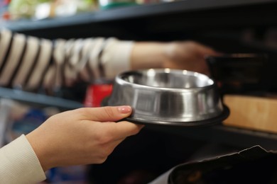 Photo of Woman choosing feeding bowl in pet shop, closeup