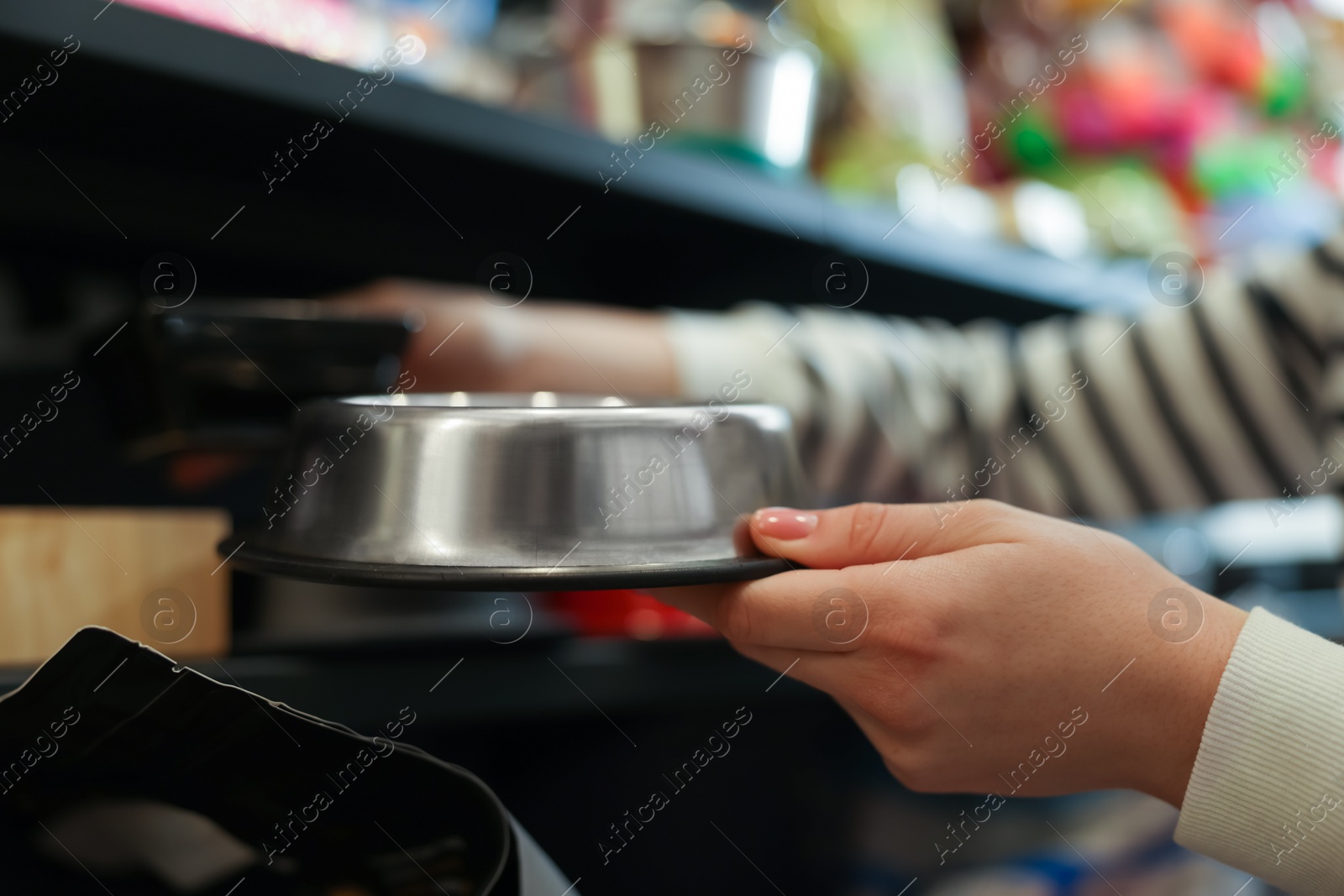 Photo of Woman choosing feeding bowl in pet shop, closeup