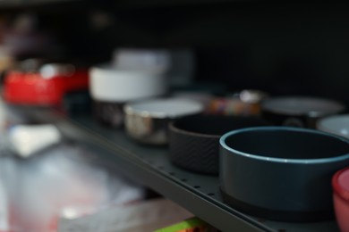 Photo of Different feeding bowls on shelf in pet shop, closeup