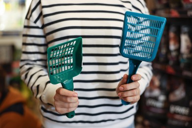 Photo of Woman with litter scoops in pet shop, closeup