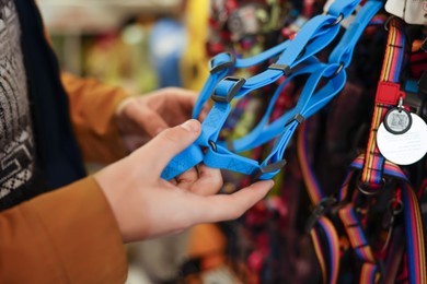 Photo of Woman choosing leash in pet shop, closeup