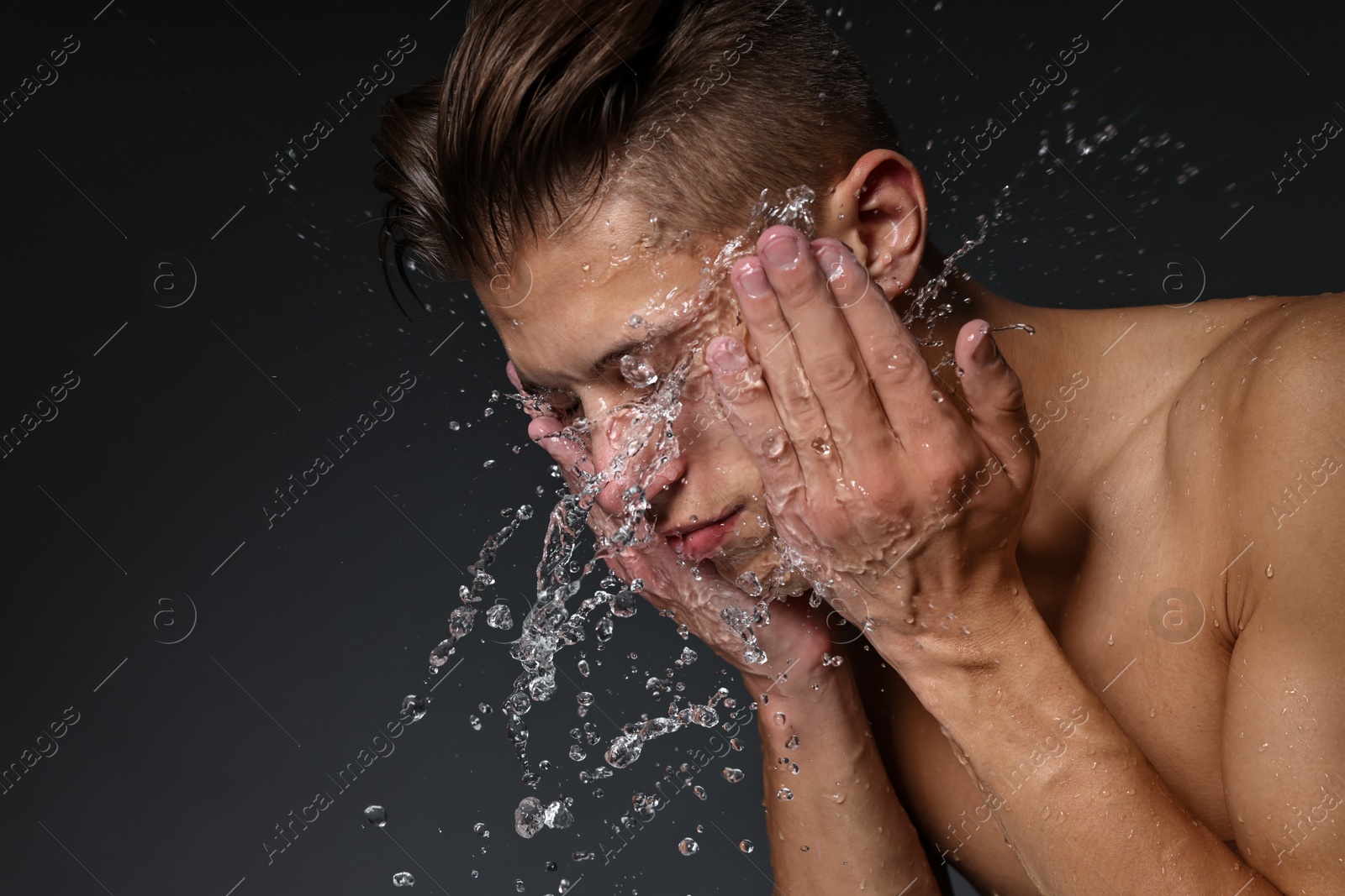 Photo of Man washing his face on black background. Space for text