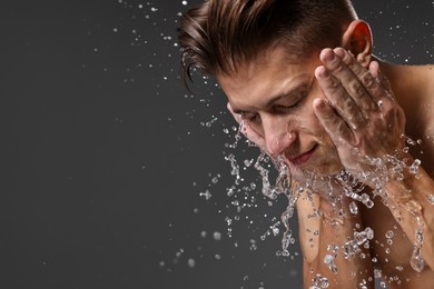 Photo of Handsome man washing his face on grey background. Space for text