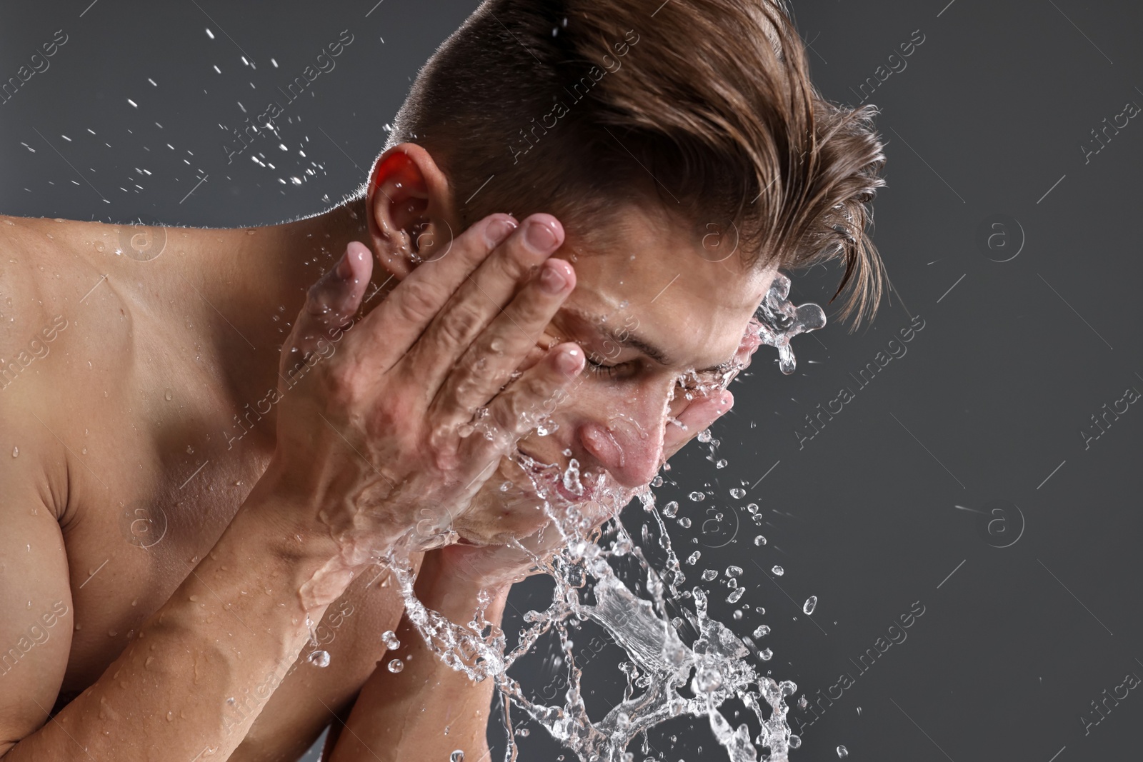 Photo of Man washing his face on grey background