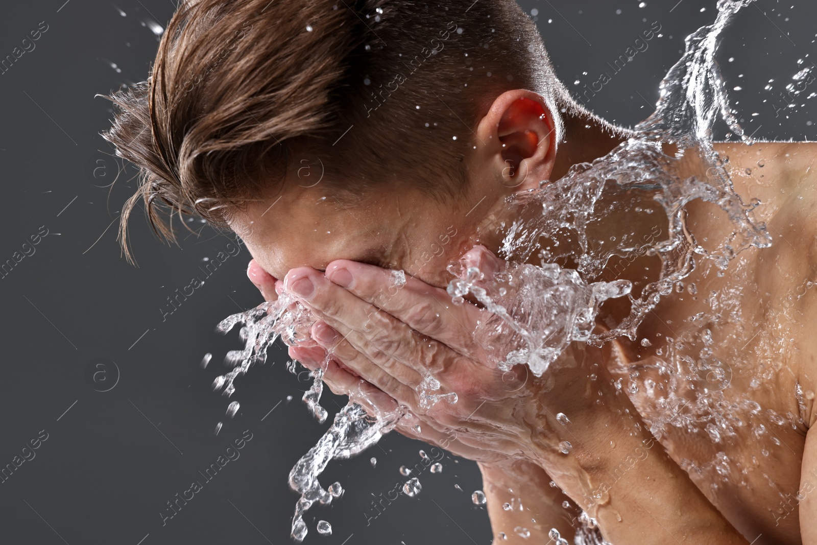 Photo of Man washing his face on grey background