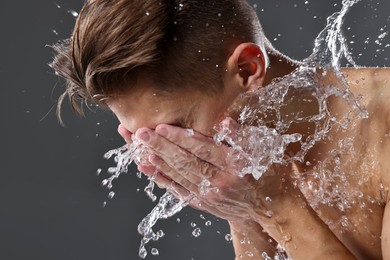 Photo of Man washing his face on grey background