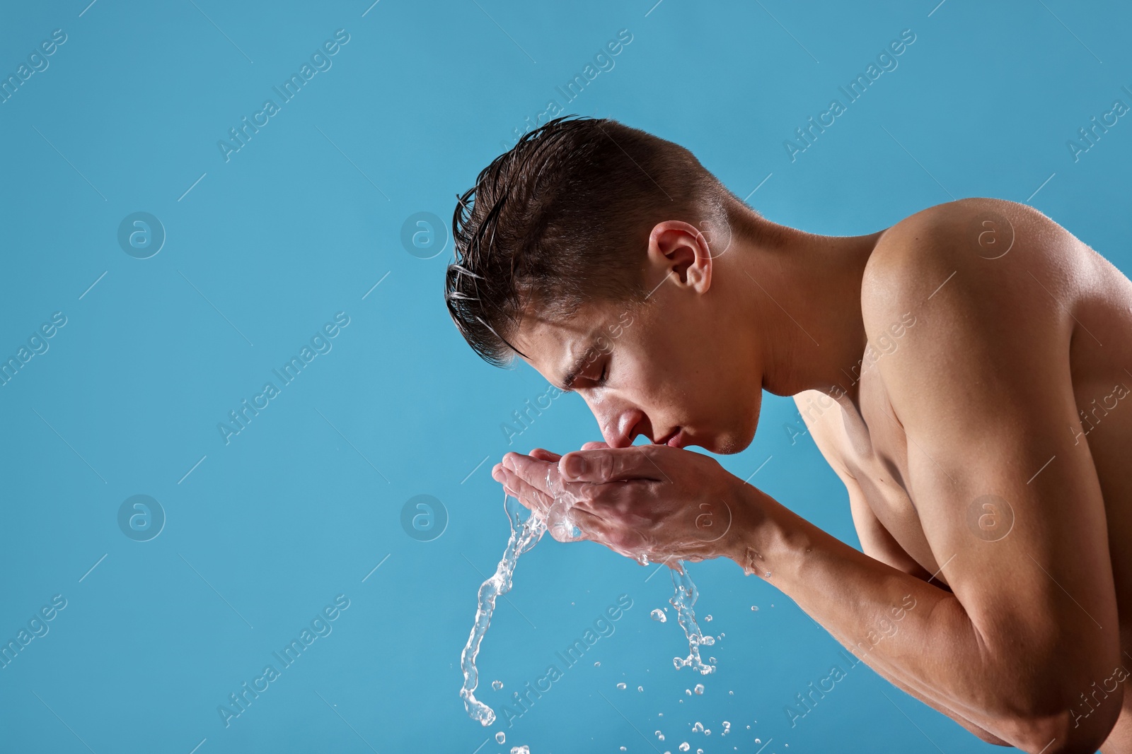 Photo of Handsome man washing his face on blue background. Space for text