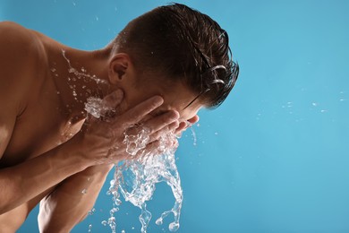 Photo of Man washing his face on blue background. Space for text