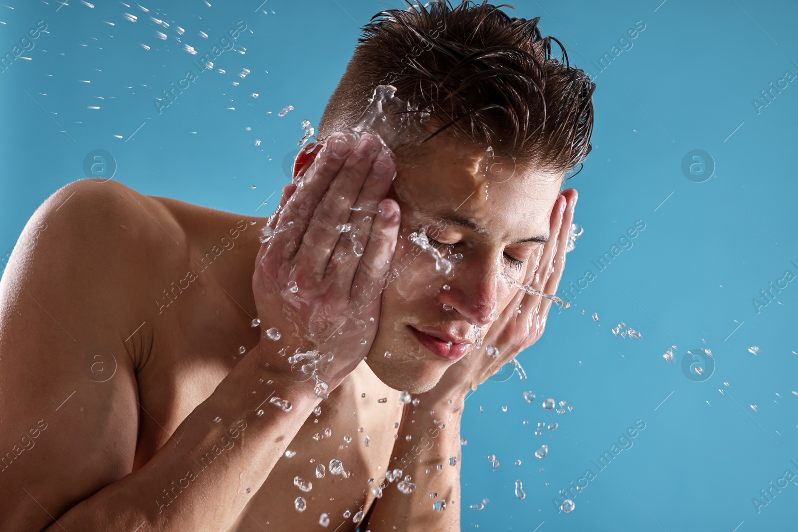 Photo of Handsome man washing his face on blue background