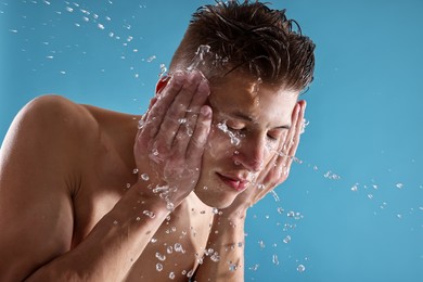 Photo of Handsome man washing his face on blue background