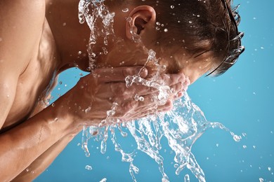 Photo of Man washing his face on blue background