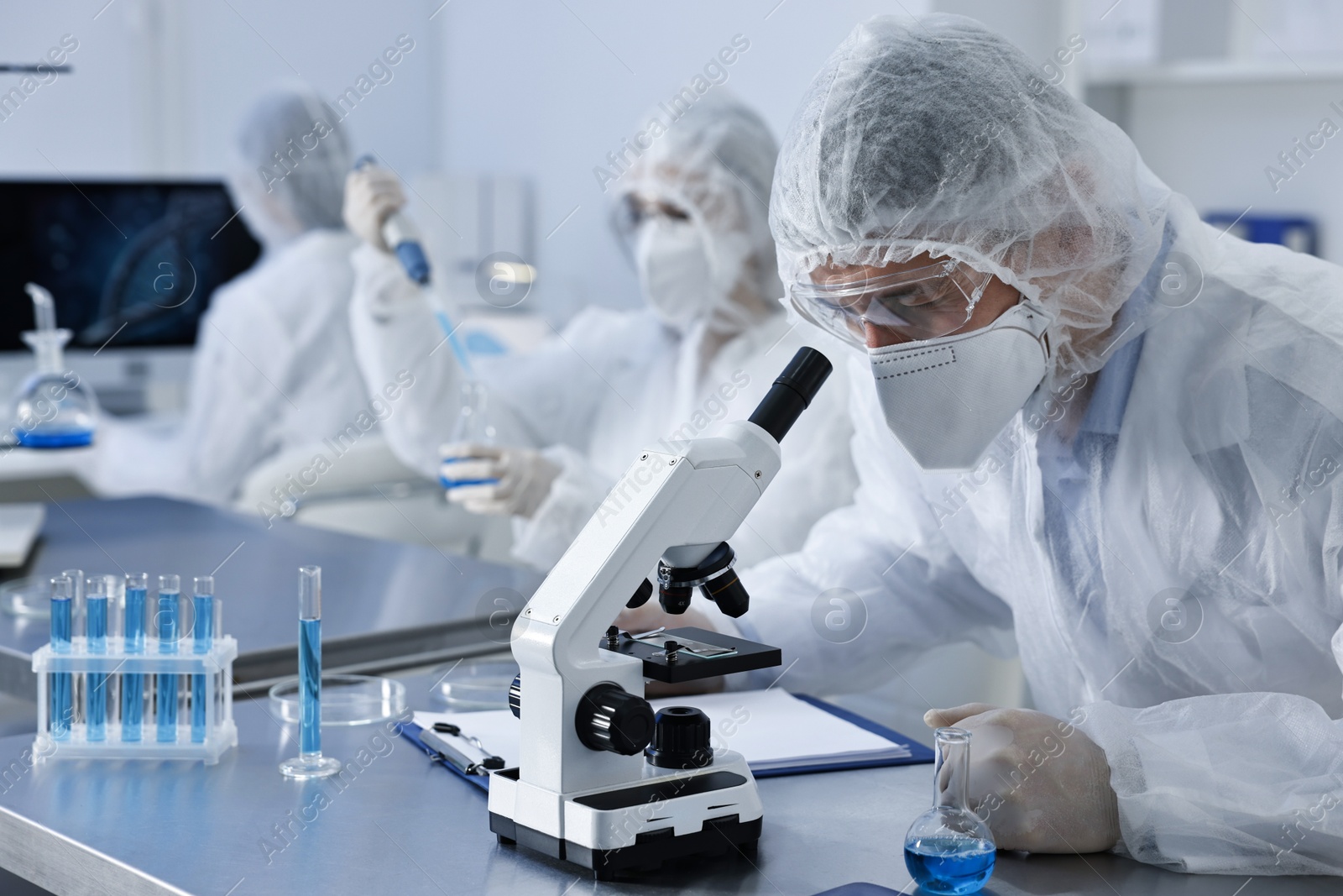 Photo of Scientist in protective suit working with microscope at laboratory