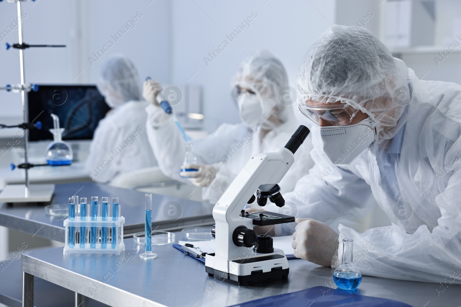 Photo of Scientist in protective suit working with microscope at laboratory