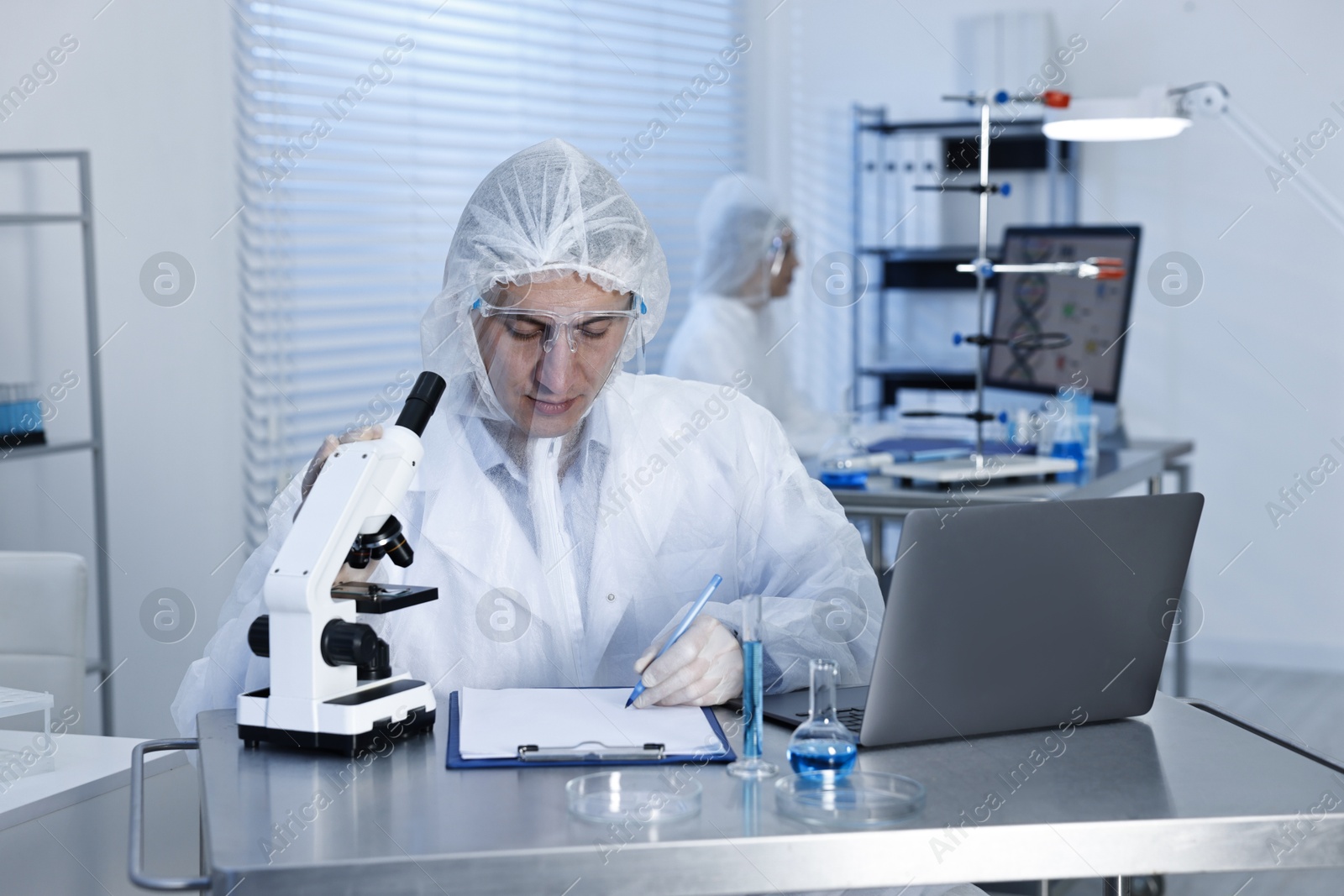 Photo of Scientist with laptop and microscope working at table in laboratory